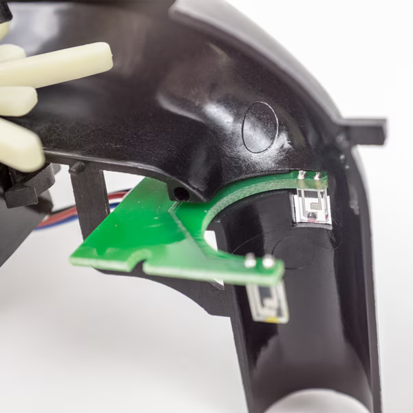 Electronic control board inside the Valken V-MAX Plus loader featuring microchip components that power the motor, manage the paddle feed system, and control LED battery indicators.